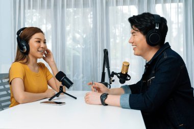 Gülümseyen radyo etkili sunucusu kulaklık takıyor kadın konuşmacı ile röportaj yapıyor sosyal medya internet sitesinden dinleyicilere bilgi paylaşıyor stüdyo kaydında sabah canlı yayın kanalı. İnfobahn.