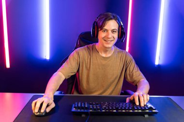 Kazanmak için çevrimiçi oyun oynayan akıllı flama makinesinin sunucu kanalı, neon ışıklı odada seçilen takım yarışması için izleyicilerle birlikte canlı yayında canlı yayında kulaklık takıyor. Bireysel.