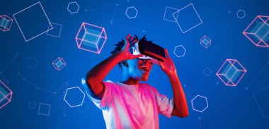 Geometrik şekillerde süzülürken mavi arka planda duran zeki çocuk. Afrikalı bir adam oyun oynuyor, VR gözlük takıyor ve sıradan bir gömlek giyiyor. Gelişmiş gerçeklik teknolojisi yenilik kavramı. Yaratıcılık.