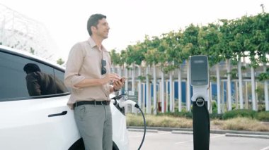 Yavaş çekim adamı, EV şarj aletini şehrin alışveriş merkezinin otoparkındaki şarj istasyonundan şarj etmek için kullandı. Sürdürülebilir şehirde EV aracı tarafından şarj edilebilir enerji olarak kullanıldı.