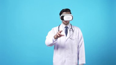 VR kulaklık ve laboratuvar önlüğü giyerken tıbbi verileri yönetmek için el ele tutuşan yetenekli bir tıp çalışanı. Profesyonel doktor mavi arka planda duruyor ve arttırılmış gerçekliği kullanıyor. Aygıt.