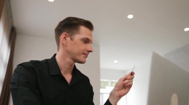 Genç adam internet bankacılığı için kredi kartlı dizüstü bilgisayar kullanıyor. İnternet üzerinden alışveriş yapıyor. Banka kartıyla modern ve kullanışlı online satın alma. Düzenle