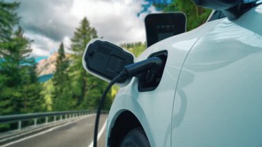 Elektrikli araç konsepti, yeşil çevre için yenilenebilir ve temiz enerjiyle çalışan EV otomobilinin varış noktasına ulaşmadan önce ormandaki şarj istasyonunun enerjisini şarj etmek için durur..