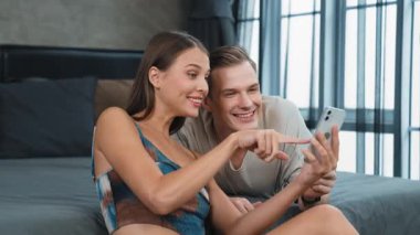Genç çift, online ödeme uygulaması ve dijital cüzdanı kullanarak kredi kartıyla ödeme yaptıktan sonra mutlu ve heyecanlı hissediyorlar. Mobil internet üzerinden alışveriş ve modern alımlar. Düzenle