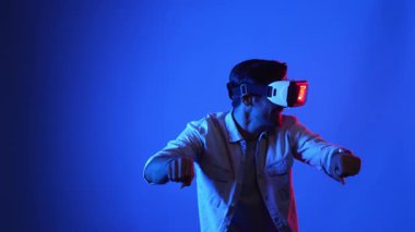 Akıllı oyuncu motosiklet sürerken yarış oyunu oynuyor. Günlük kıyafetleri olan, sanal gerçeklik gözlüğü takan ve meta veriye veya sanal dünyaya giren bir erkek model. Teknoloji. Aygıt.