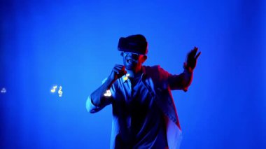 Sanal gerçeklik gözlüğü takan ve havada süzülen notalı bir şarkı söyleyen mutlu dansçı. Dans ederken ve hareketli adımlar atarken sanal gerçeklik kulaklığı kullanan çekici bir adam. Aygıt.