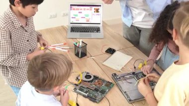 Öğretmenler tableti tutarken ve BTMM teknoloji sınıfında çevrimiçi yazılımı açıklarken ana ekranda dizüstü bilgisayar mühendisliği komut yazısıyla birlikte çalışan çeşitli öğrenci grubu. Pedagoji.