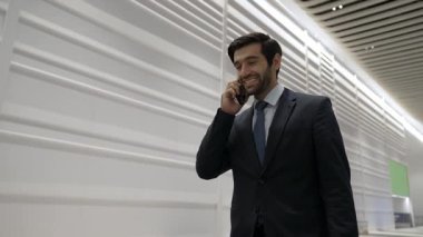 Profesyonel lider, işe başlama projesi için iş ekibini ararken ofise doğru yürüyor. Yakışıklı erkek lider toplantı odasına giderken telefonla pazarlama planı hakkında rapor veriyor. Sevinçli..