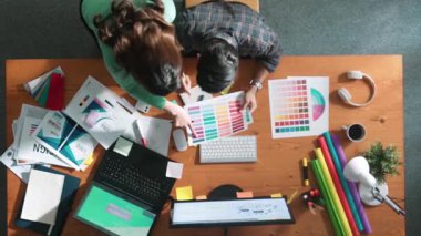 Akıllı tasarımcının renkli paletlerden renk seçmesine yardım ederken yukarıdan aşağı görünümü. Dizüstü bilgisayardan logoya bakarken birlikte çalışan ve planlayan iş adamlarının hava görüntüsü. Sempozyum.