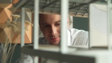 Kafkasyalı mimar mühendisinin yakın çekimi ev inşaatını denetlemek ve bina malzemelerini kontrol etmek. Proje yöneticisi modele dikkatlice bakarken kalemi işaret ediyor. Yönlendirici.