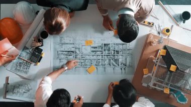 Becerikli mühendis ekibinin ev inşaatından bahsedişinin en alt görüntüsü. Mimar ya da tasarımcı grubunun planlar hakkında beyin fırtınası yapmak için tartışan ve yazan hava görüşü. Hizalama.