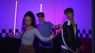 Çok kültürlü break dans takımı mor neon ışıkla stüdyoda müzik yapıyor. Stüdyoda farklı arkadaşlara bakarken serbest dans eden enerjik sokak dansçıları grubu. Çılgınca. Mutluluk.