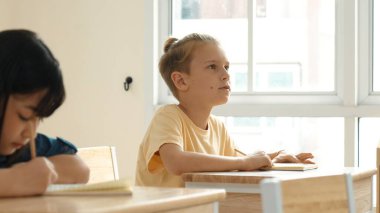 Zeki öğrenci sınıfta otururken öğretmenlerin sorularına cevap verir. Tahtaya bakarak ve ilköğretim sınıfına katılarak çeşitli çocuklar öğreniyor ve öğreniyor. Eğitim konsepti. Pedagoji.