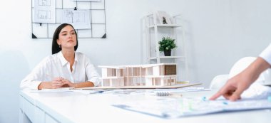 Profesyonel mühendis ekibinin yakın plan görüntüsü modern ofisin inşaatı hakkında tartışılıyor. Erkek mühendis haritayı masaya koyarken güzel mimar not alıyor. Tertemiz..