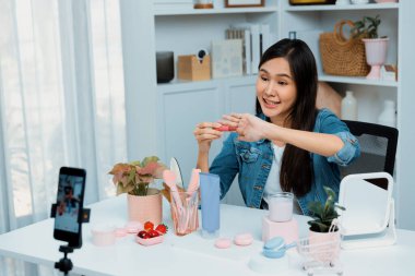 Genç, güzel Asyalı kozmetik makyaj ruju matte pastel rengini modern odadaki sosyal medyada kol testi tanıtımında en çok satanlar listesinde gösteriyor. Taktik.