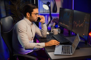 Tüccar akıllı işadamı komisyoncuyu ya da ortağını arıyor, modern evde kârlı bir finans teknolojisi olan neon aydınlatma ofisindeki bilgisayardaki dinamik borsa yatırımlarını analiz ediyor. Tahmin et..