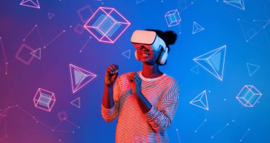 VR gözlüklü Afrikalı kız mavi ve pembe arka planda duruyor ve yüzen geometrik şekle bakıyor. Heyecanlı insan görsel gerçeklik dünyasına giriyor. Teknoloji yeniliği. Yaratıcılık.