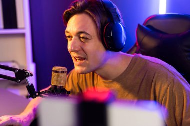 Oyun kanalı, online oyun oynayan akıllı flamalı oyun sunucusu, kulaklık takan, neon ışıklandırma odasındaki takım oyuncusuyla akıllı telefondan canlı yayında konuşan izleyiciler. Bireysel.