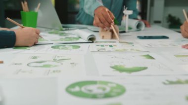 Çeşitli bir ekip, bir iş analizi projesi üzerinde işbirliği yaparak, modern bir ofis alanındaki doküman ve grafikleri inceleyerek stratejik planlama ve takım çalışmasına odaklanır. SACTR