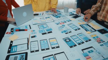 Profesyonel bir ekip cihaz prototipleri ve kullanıcı arayüzü tasarımları üzerinde, dijital çözümlerde yaratıcılığı ve yeniliği gösteren modeller ve kırtasiyelerle çevrelenmiş olarak işbirliği yapar. SACTR