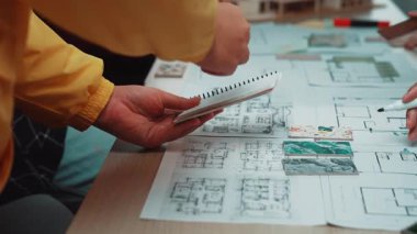 Mimari planları ve ölçekli bir modeli olan ve yaratıcılık ve takım çalışmasını temsil eden çeşitli bireylerin ellerini gösteren ortak bir tasarım oturumu. SACTR