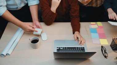 Sofrada dizüstü bilgisayarlar ve çeşitli yaratıcı materyallerin yer aldığı modern bir ofis ortamında ortak bir projede yer alan çeşitli profesyoneller grubu. SACTR