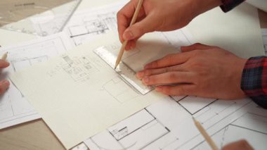 Mimari ekipmanlarla toplantı masasında ev tasarımı üzerine profesyonel mühendis ekibi tartışması ve modern ofiste bina planı dağılımı. Eline odaklan. - Yakın çekim. Tanımlama.