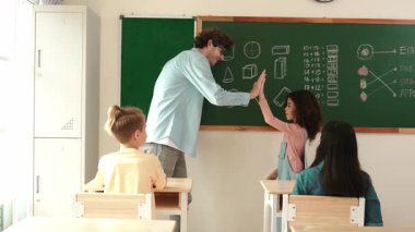 Afrikalı kız tahtada yazı yazarken, matematik dersinde çalışması için Kafkas öğretmeniyle beşlik çakıyor. Öğretmen çocuğa bakarken öğrenci soruya cevap verir. Pedagoji.