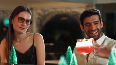 Grup arkadaşı ya da çift, gece kulübündeki neon karlı çam ağacında şenlik için özel bir menü içeceği tatmak için tezgahta punç kokteyli içmeyi tartışıyor. Vinosity.