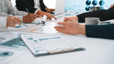 Çeşitli profesyonellerden oluşan bir grup, iş stratejileri ve içgörüleri tartışırken, modern bir ofis masasındaki çizelge ve verileri analiz ederek dinamik bir toplantıya girişiyor. SACTR