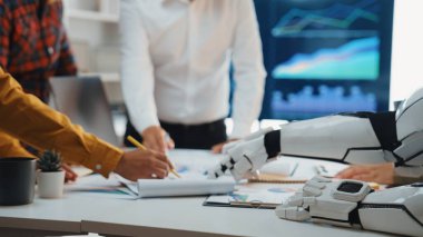 Veri analizi ve yenilikçi iş stratejilerindeki takım çalışmasını gösteren, insanlarla bir robot arasındaki dinamik ofis sahnesi. Noogenesis