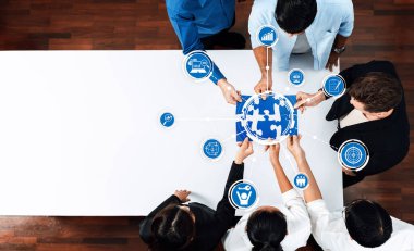 Çeşitli profesyonellerden oluşan bir grup, küresel takım çalışmalarını ve çeşitli dijital simgeleri sembolize eden, yenilik ve strateji içeren bir masa üzerinde işbirliği yapıyor. Dostluk