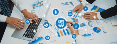 İşletme yönetiminde takım çalışmasını gösteren dinamik bir ofis sahnesi. Elleri dizüstü bilgisayar ve grafik ve verilerin görsel analizi üzerinde çalışıyor. Dostluk