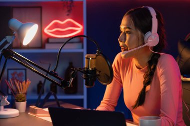 Geceleri podcast 'te olumlu konuşmalar yapan, pembe neon ışıklı modern stüdyoda sunum için dizüstü bilgisayar kullanan, gülümseyen, genç, güzel Asyalı bir etkileyiciydi. Taktik.