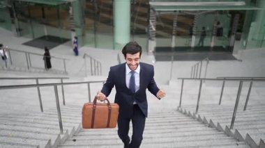 Terfi alma, satışları artırma, maaşları artırma konusunda iyi haberleri kutlamak için dans eden mutlu iş adamı şehirde geçmişi bulanık bir şekilde merdivenlerden çıkarken. Neşeli bir ruh hali. Sevinçli..