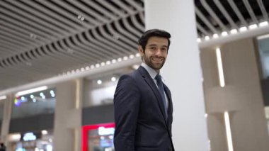 Beyaz arka planda dururken kameraya bakan bir iş adamı. İş elbisesi giyerken kameraya gülümseyen başarılı adamın yakın çekimi. Yönetici, kameraya bak. Hareket eden kamera. Sevinçli..