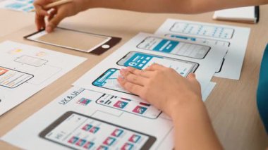 Mobil uygulama için kullanıcı arayüzü prototipi ya da masadaki program modeliyle birlikte web sitesi planlaması yapan bir şirket çalışanı. UX UI tasarımcısı kullanıcı dostu arayüz planını dikkate alır. Sinerjik