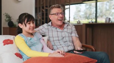 Büyükbaba ve torun birlikte TV 'de ilginç bir eğlence medyası izliyorlar. Eski üst düzey kullanım teknolojisi, genç nesil çapraz nesil ile iletişim kurarak aile bağlarını güçlendiriyor. Uyumsuzluk.