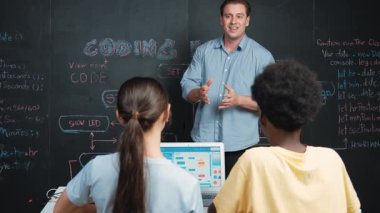 Çeşitli öğrenciler mutlulukla kollarını kaldırırken yakışıklı öğretmen başarılı bir projeyi kutlamak için el çırpıyor. Eğitmen liseli çocukları programlama eğitimine ilham vermek için alkışladı