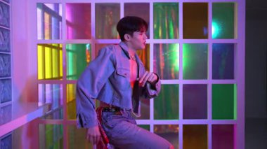 Kameraya bakarken kollarını esneten seksi kıyafetli Asyalı dansçı. Profesyonel sanatçı gece kulübünde renkli neon ışıkları canlı bir şekilde dururken serbest stil dansı yapıyor. Mutluluk.