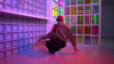 Yakışıklı, beyaz tenli sanatçı kurşun ışıkla dans etmek için dans ediyor. Güneş gözlüklü, şapkalı çılgın hippi dans ediyor ve modern gece kulübünde serbest dans dinlemenin tadını çıkarıyor. Mutluluk.