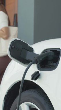 Bir kadın evinde elektrikli araç şarj aletinin fişini çekiyor. İlerici bir yaşam tarzında elektrikli araçların kullanımı, temiz ve sağlıklı bir çevreye katkıda bulunur..