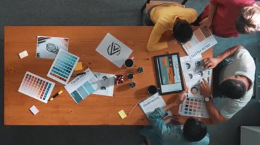 Proje yöneticisi renk paletleri seçerken tasarımcının tablete baktığı yukarıdan aşağıya hava görüntüsü. Profesyonel grafik tasarımının en üst görüntüsü ve logoya bakın. Yetenekli ekip grafikleri seçiyor. Sempozyum.