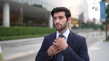 Profesyonel iş adamı yolda yürürken kravatı ayarlar. Yönetici şehre bakarken takım elbise giyiyor. Yatırımcı görüşmeye gitmeden önce kendini kontrol etmiş. Arka plan bulanık. Sevinçli..