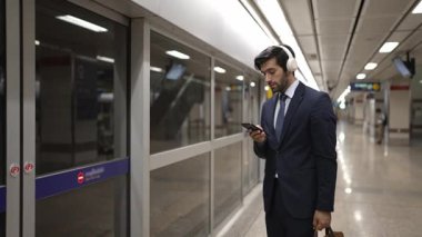 Proje yöneticisi tren istasyonunda şarkı seçmek için cep telefonu tutarken kulaklık takıyor. Zeki iş adamı bulanık geçmişi olan treni beklerken saati kontrol ediyor. Sevinçli..