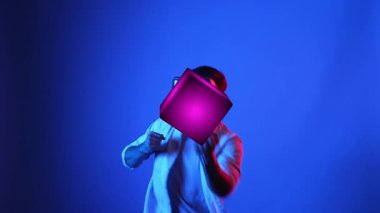 Meta evreni bağlamak için VR gözlük takarken yetenekli oyuncu boksörleri ve yüzen kutuları yumrukluyor. Erkek model, egzersiz yaparken ve neon arka planda dururken sanal gerçeklik gözlüğü kullanıyor. Aygıt.