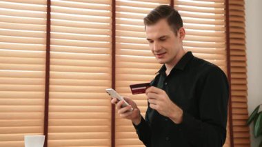 Masada oturan genç adam kredi kartıyla ödeme yapmak için akıllı telefondaki dijital cüzdanı ve uygulamayı kullanıyor. Mobil internet üzerinden alışveriş ve modern alımlar. Düzenle