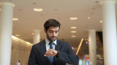 Kafkasyalı zeki iş adamı iş arkadaşını beklerken saate bakıyor. Bulanık geçmişiyle alışveriş merkezinde dikilirken yönetici takım elbise giyiyor. Yatırımcı mavi takım elbise giyer. Sevinçli..