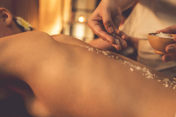 Крупным планом пару клиентов, имеющих пилинг лечение в роскошном спа-салоне с теплой свечи окружающей среды. Косметическое лечение бальзамическим скрабом в Health spa scrub. Quiescent