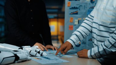 İki iş adamı modern bir ofiste veri analizi üzerinde odaklanmış bir işbirliği içindedir. Anahtar noktalara işaret ederken grafikleri ve grafikleri gözden geçirirler. Noogenesis